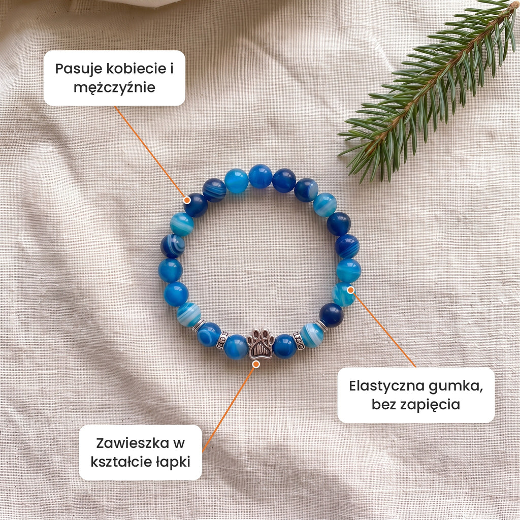 Cechy: Bransoletka Błękitna Toń. Zawieszka w kształcie łapki, elastyczna gumka bez zapięcia, pasuje kobiecie i mężczyźnie